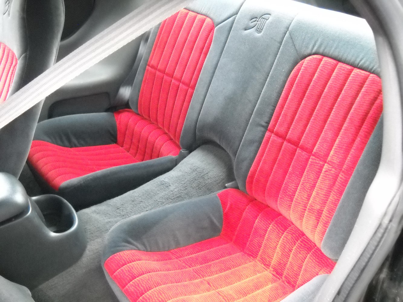 Rear car seat with red and black upholstery and seatbelt