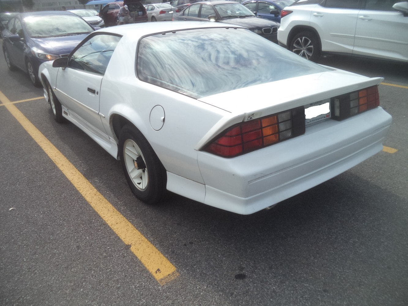 Rear and side profile of a white sports coupe with distinctive taillights and angular body design.