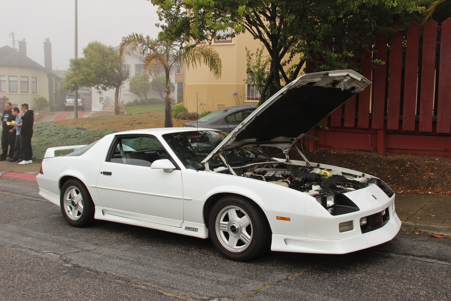 White sports coupe with open hood showing engine compartment