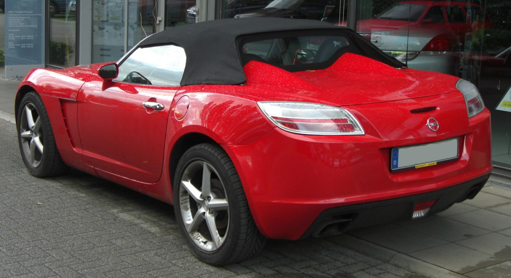 Rear view of a red convertible roadster with soft top and distinctive taillights