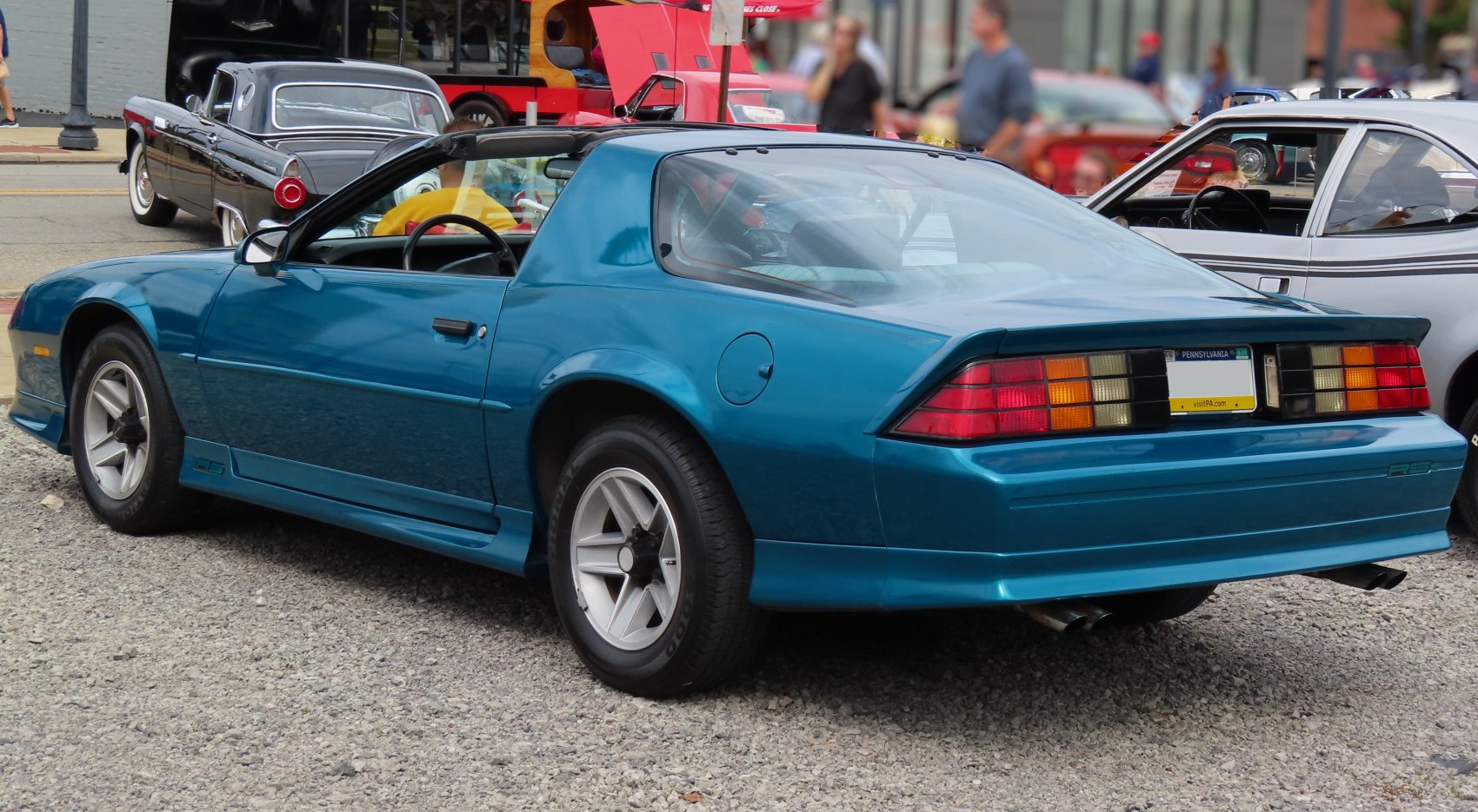 Blue T-top sports coupe with distinctive rear lights and dual exhaust
