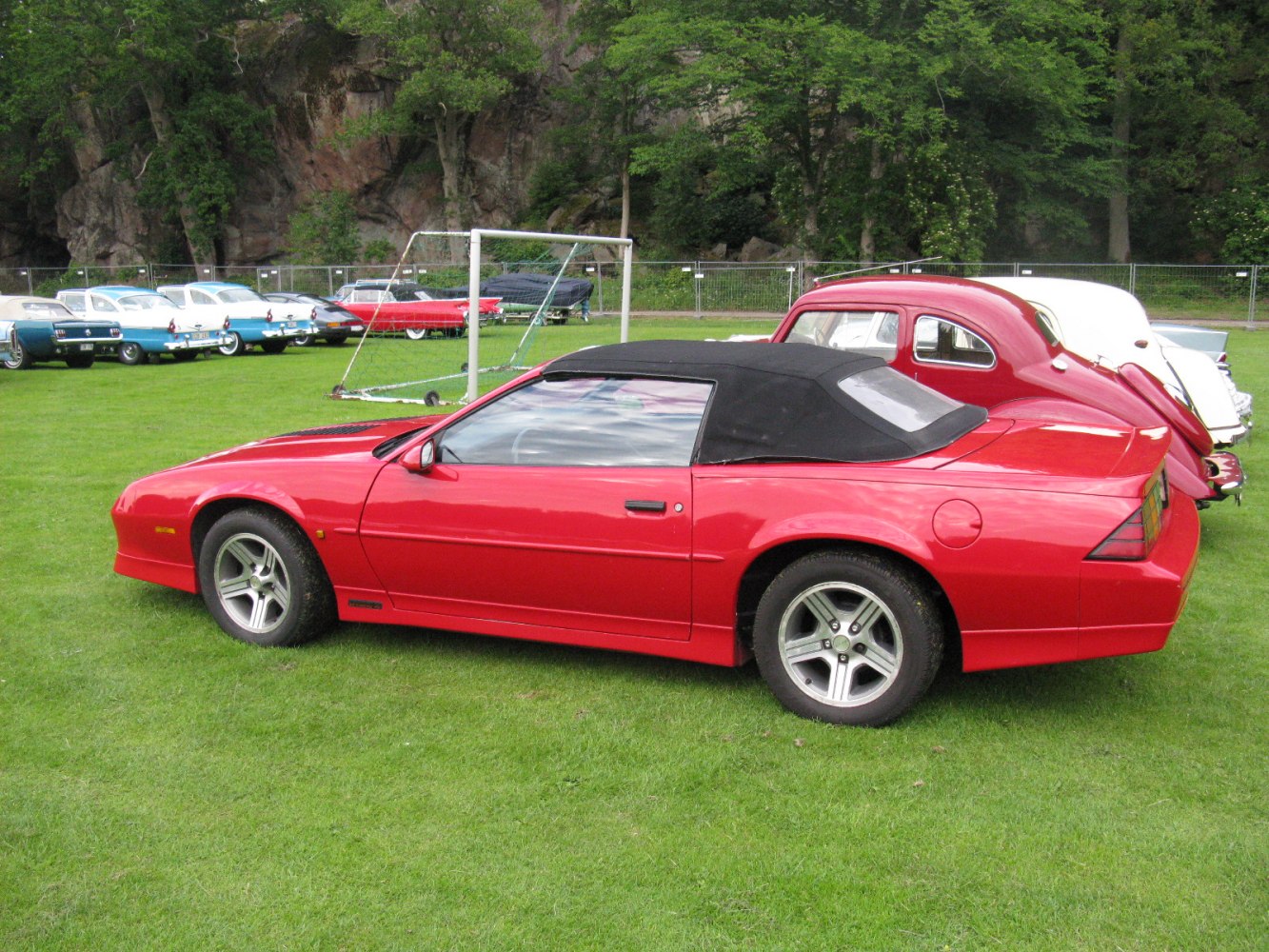 Red convertible with black soft top, side view.