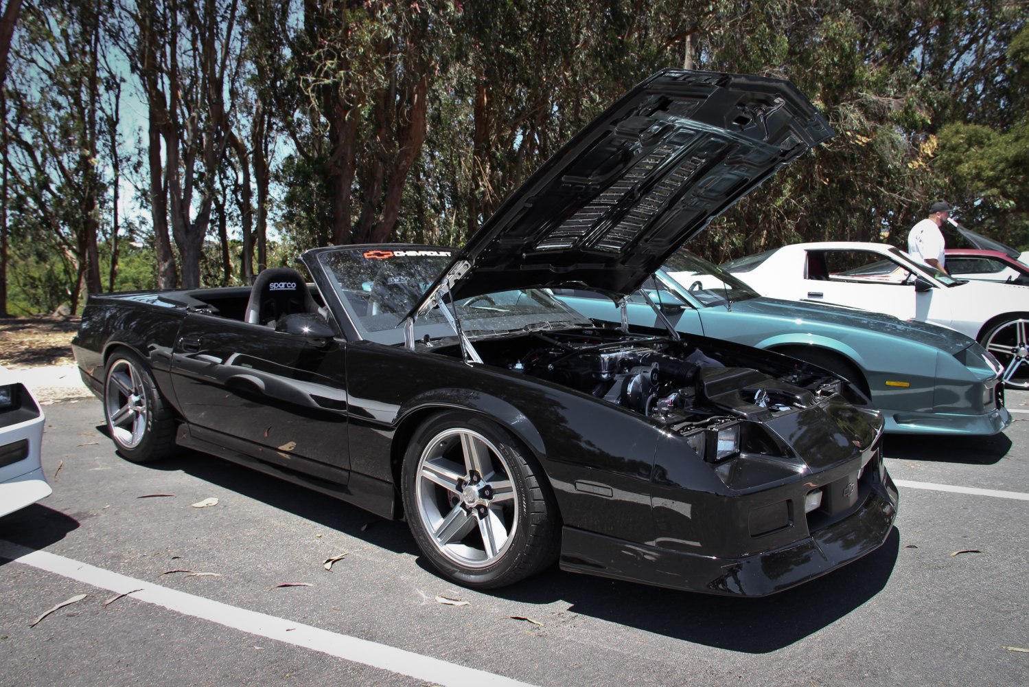 Black convertible with open hood showing detailed engine bay and aftermarket wheels