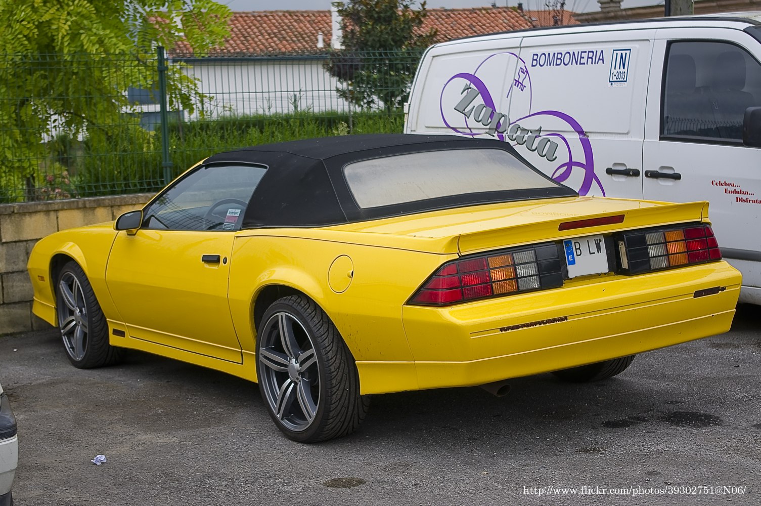Convertible with black soft top and aftermarket rims from rear