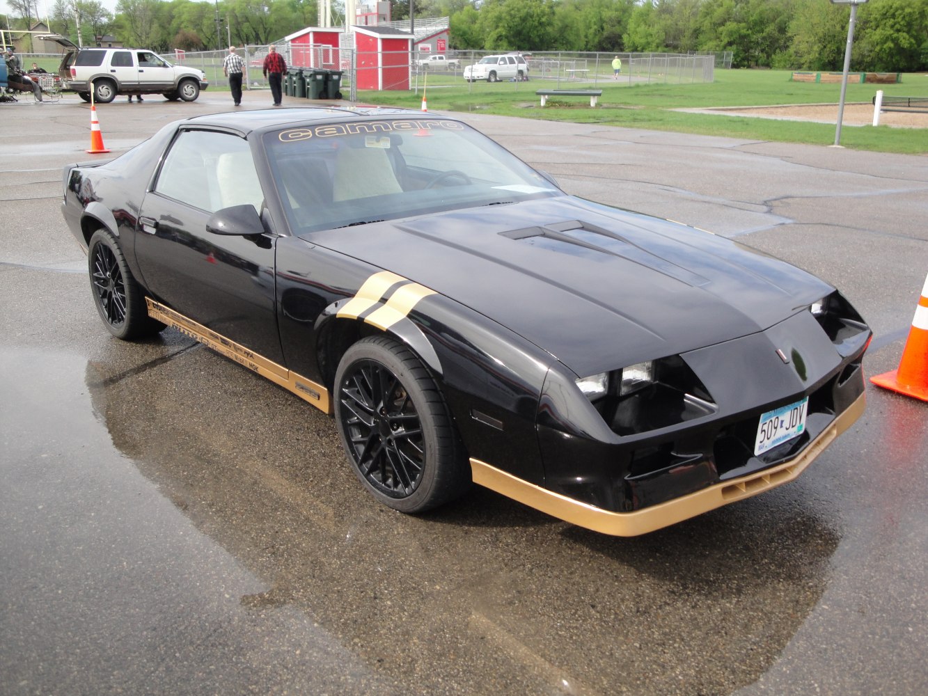 Black Chevrolet Camaro III with gold racing stripes and custom wheels