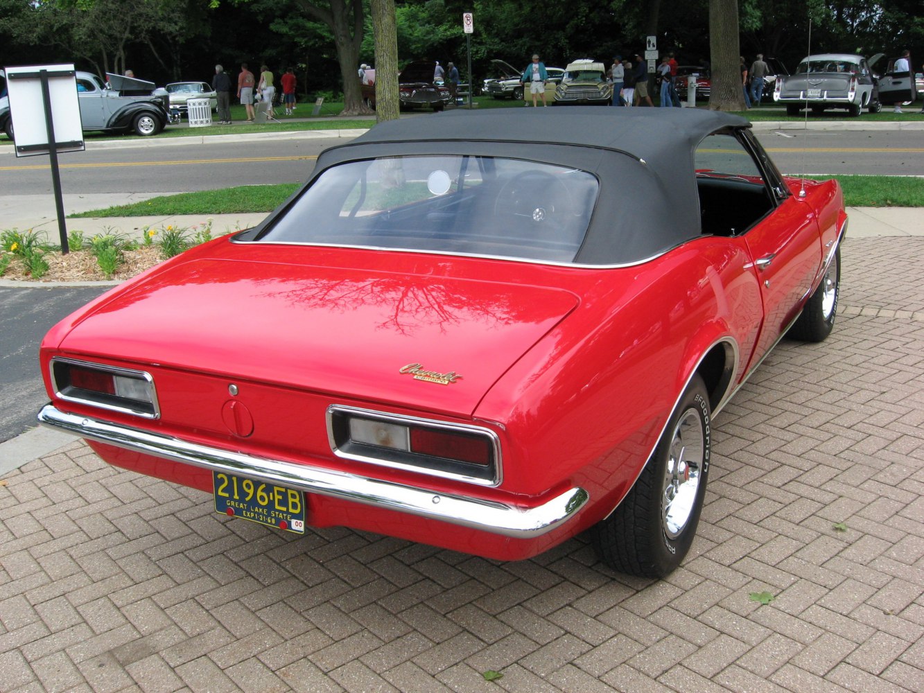 Rear view of a red convertible with black soft top and chrome bumper.