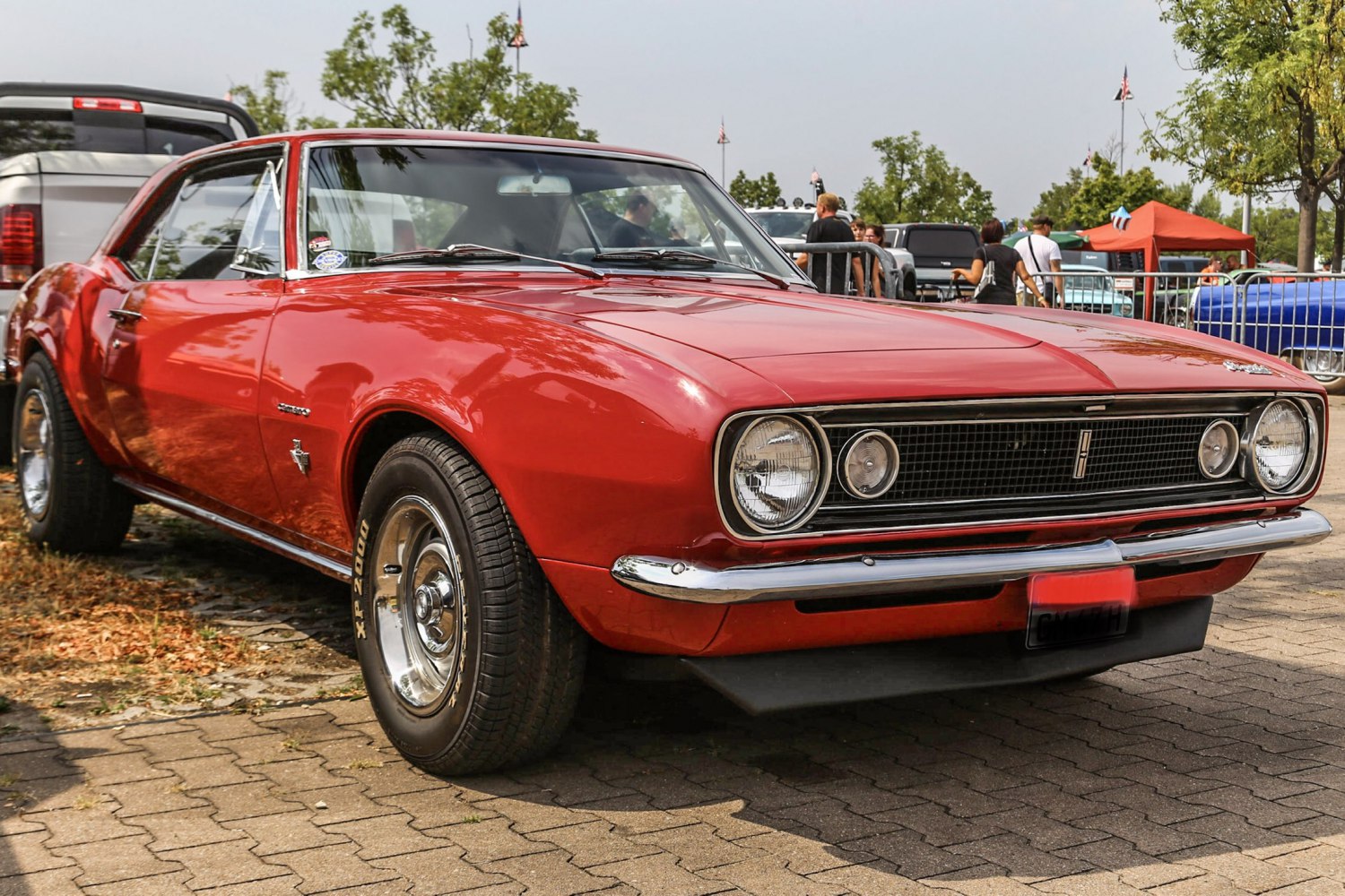 Front view of classic red muscle car with round headlights and chrome bumper