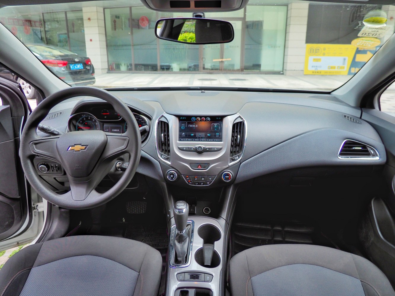 Dashboard, steering wheel, infotainment screen, gear shift, and climate control layout.