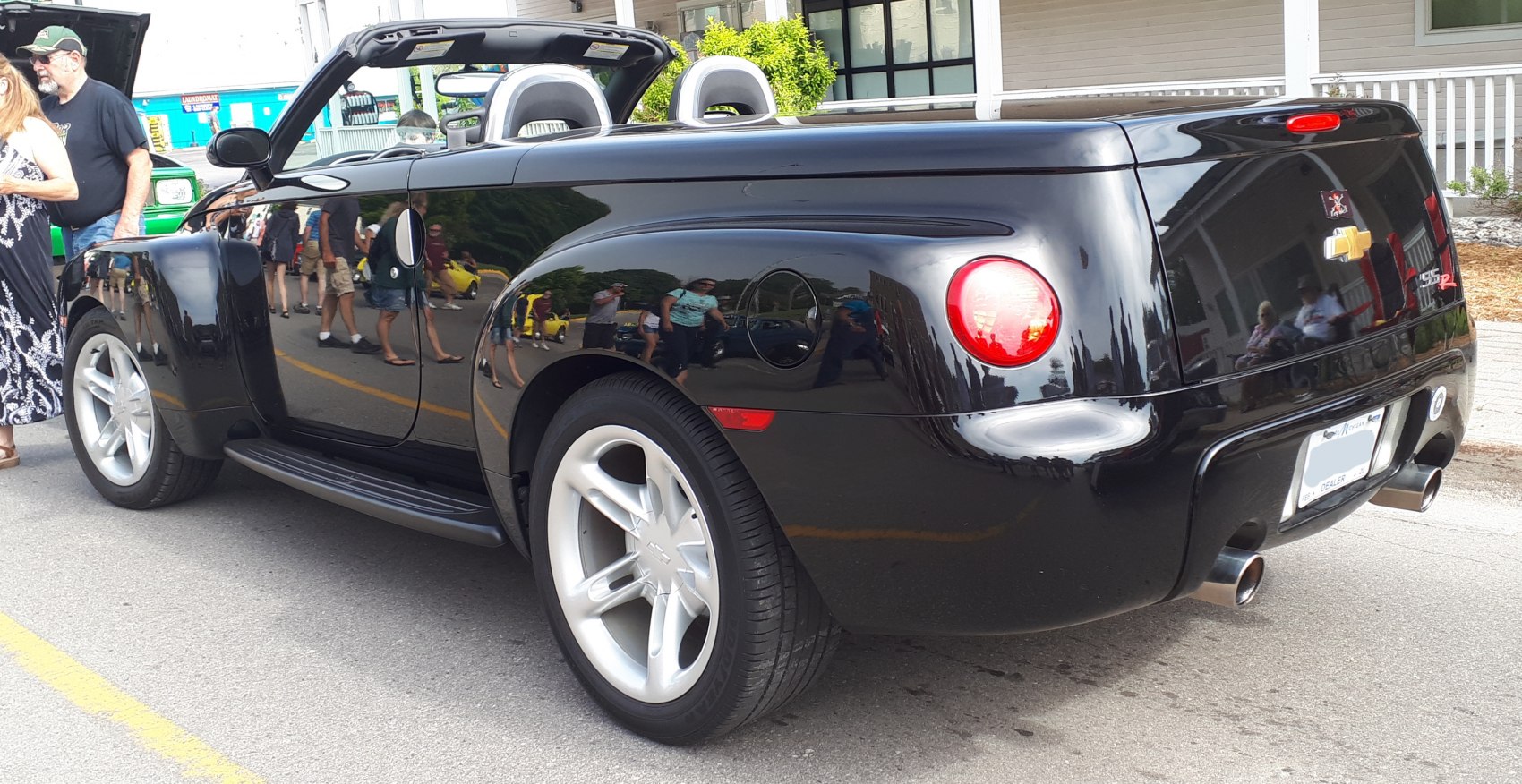Rear view of black convertible pickup with dual exhausts and curved design