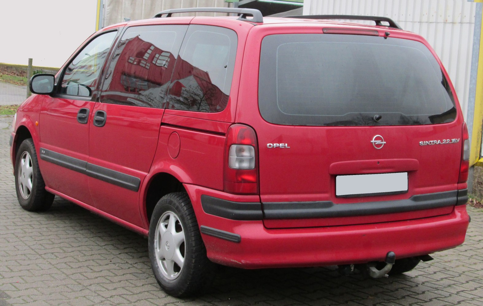 Rear and side view of red MPV with sliding doors and roof rails