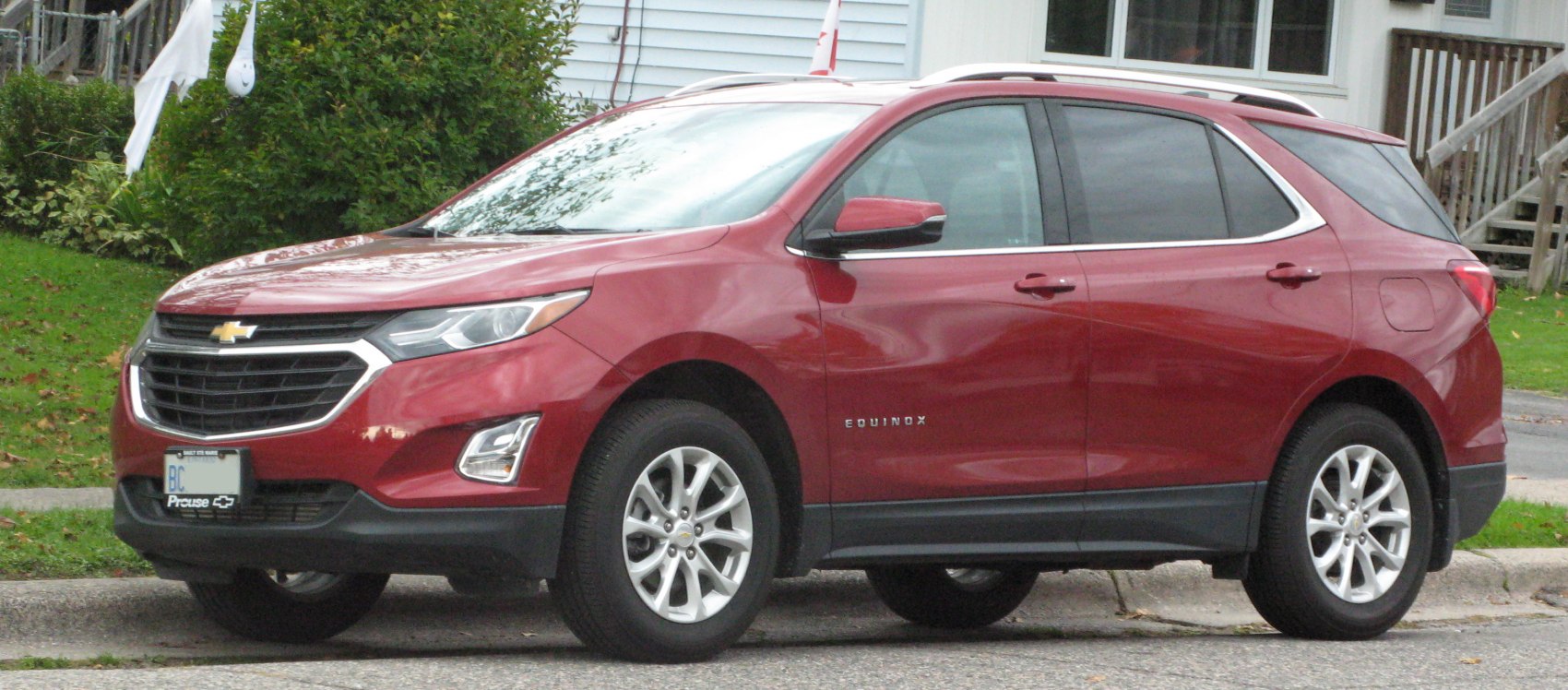 Front-side view of a red SUV with alloy wheels and roof rails