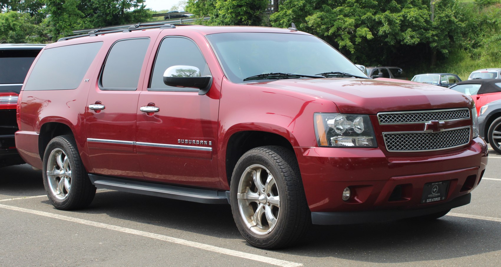 Front side view of a large red SUV with chrome wheels and tinted windows