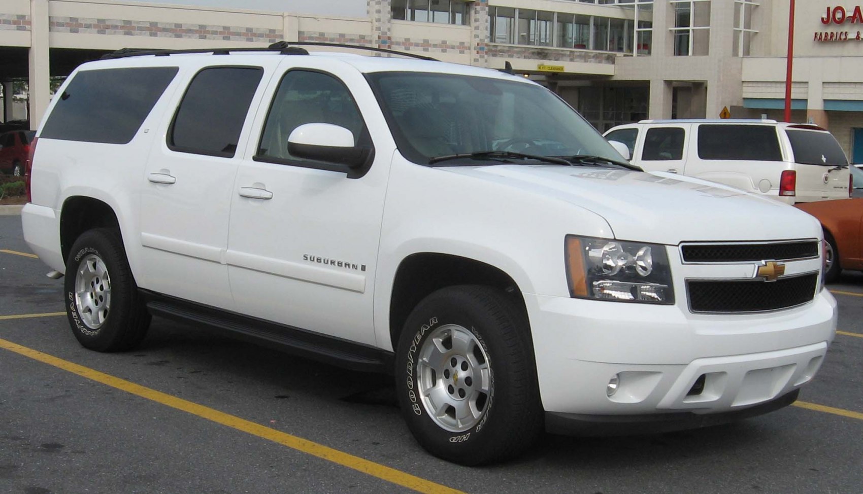 Front-side view of a large white SUV with distinct grille and headlights
