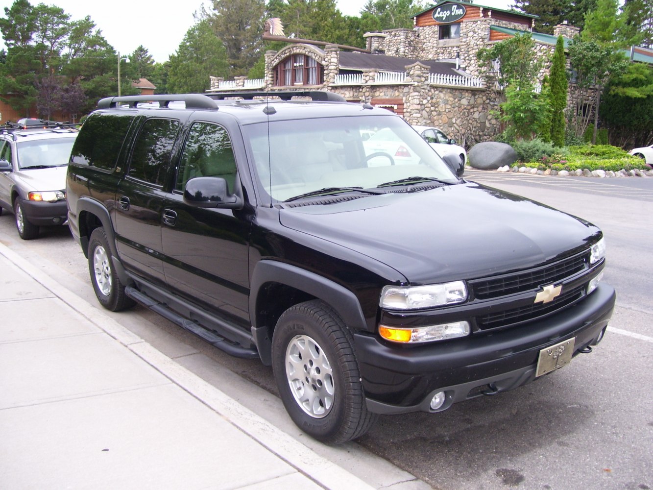 Large black SUV front-side view with roof rails and running boards