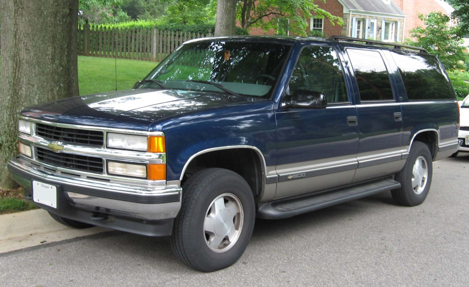 Front side view of large SUV with chrome grille and running boards