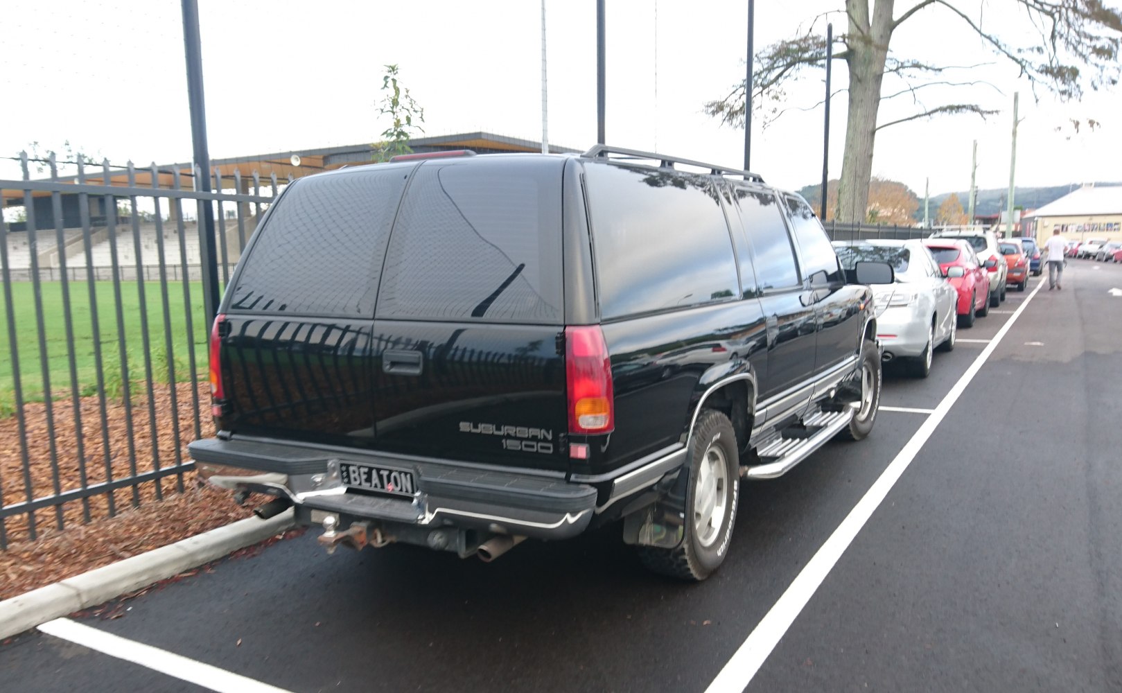 Rear view of an SUV with tinted windows, roof rack, and side steps