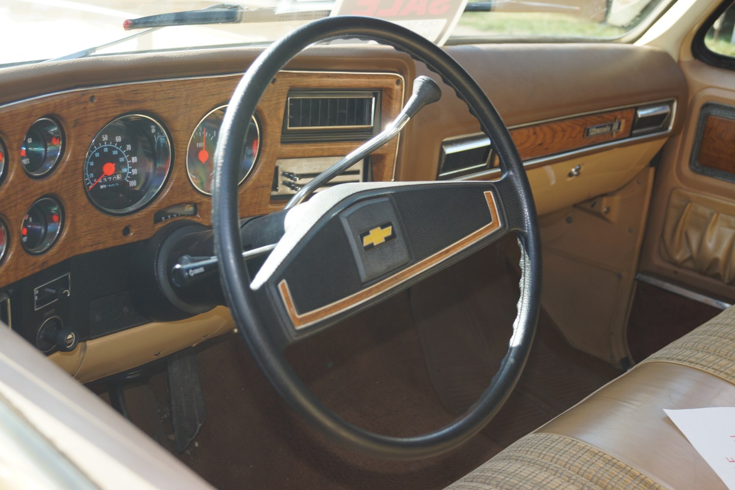 Classic steering wheel and woodgrain dashboard of a 1970s vehicle interior