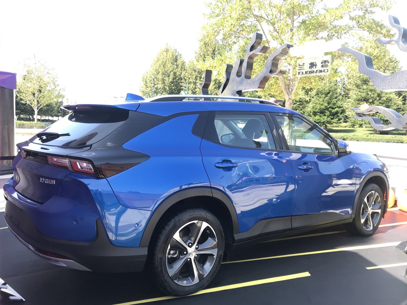 Rear-side view of blue SUV with black roof and alloy wheels