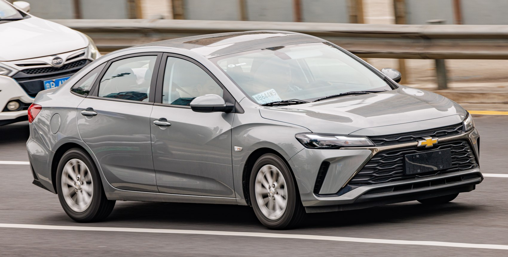 Silver sedan in motion, front and side view with distinct grille and headlights