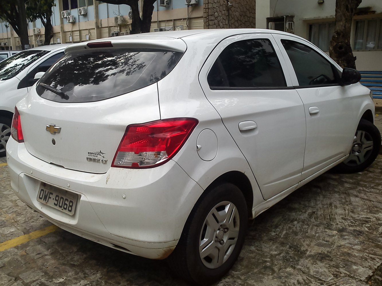 Rear view of a white five-door hatchback with roof spoiler and tail lights.
