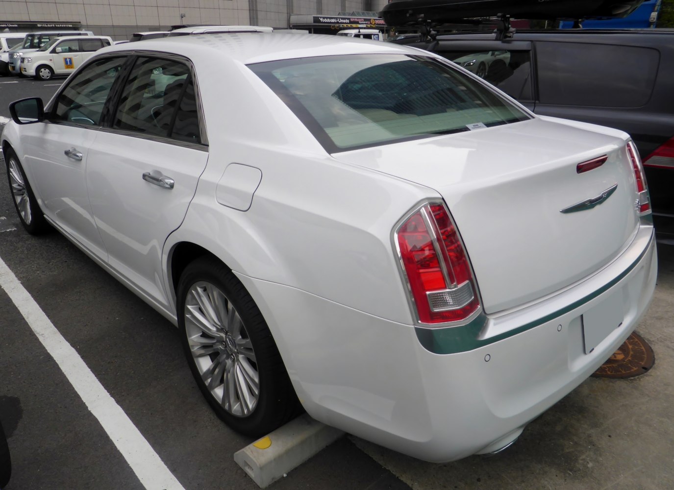 Rear view of white luxury sedan with vertical tail lights and chrome trim