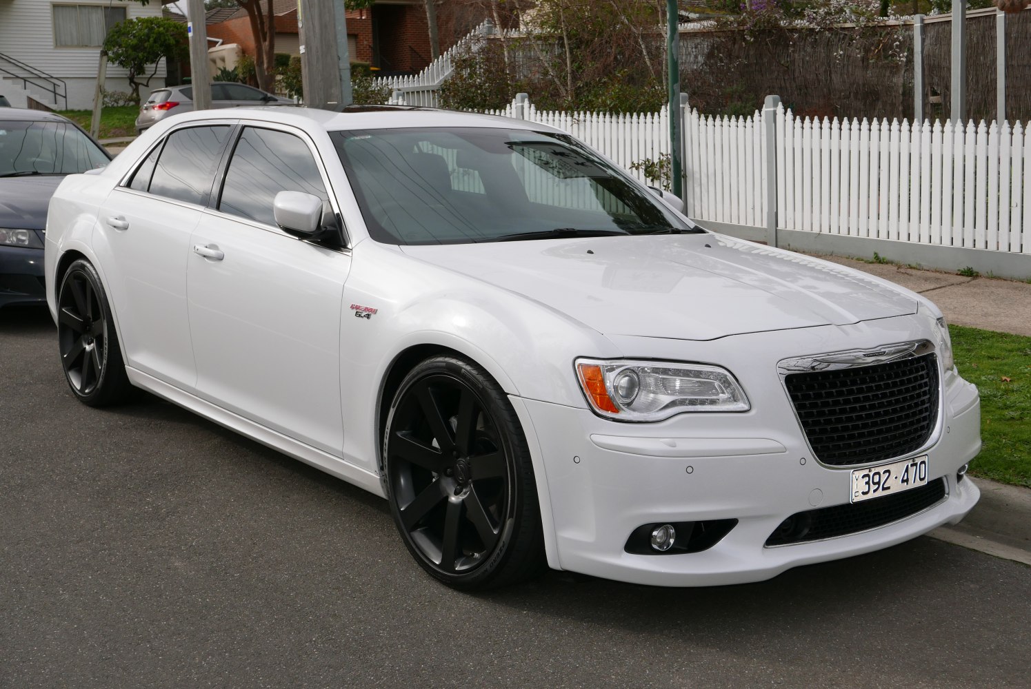 White sedan with black alloy wheels and 6.4L engine badge