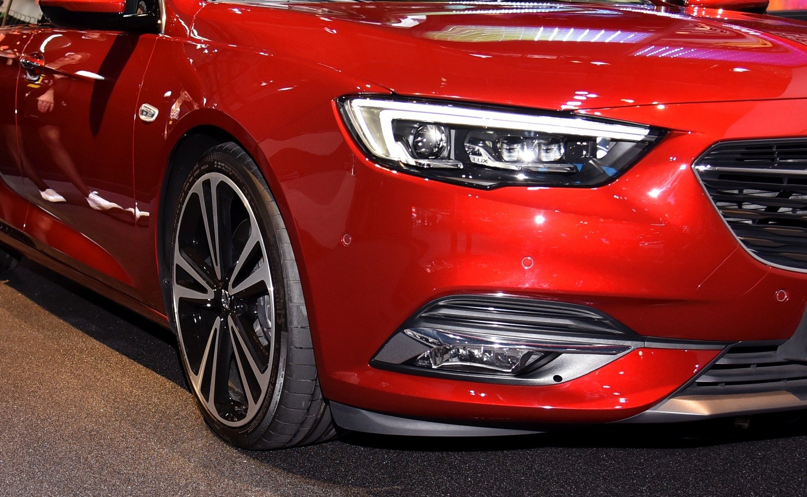 Closeup of LED headlight and alloy wheel on red car front