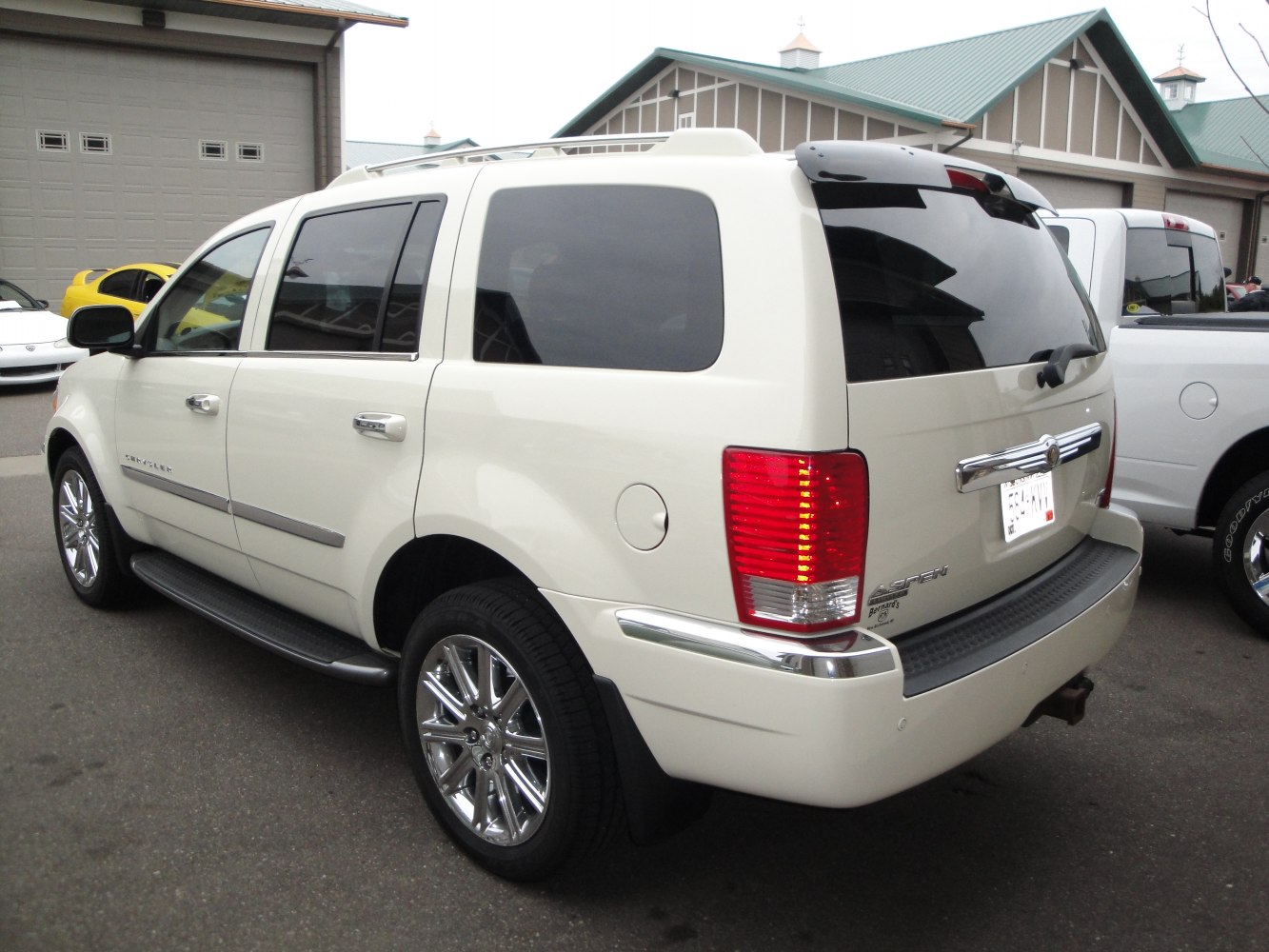 Rear side of SUV with chrome wheels, running boards, tinted rear windows