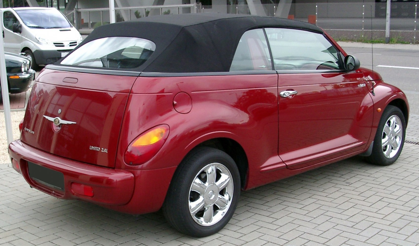 Red convertible with black soft top and chrome wheels.