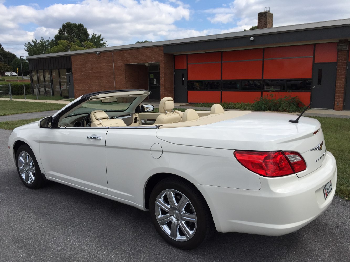 Rear side view of white convertible with beige interior and chrome wheels