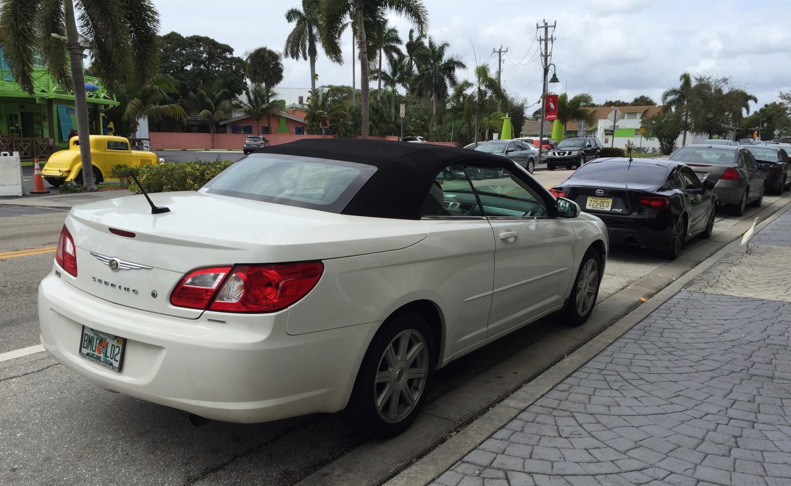White convertible with black soft top roof rear side