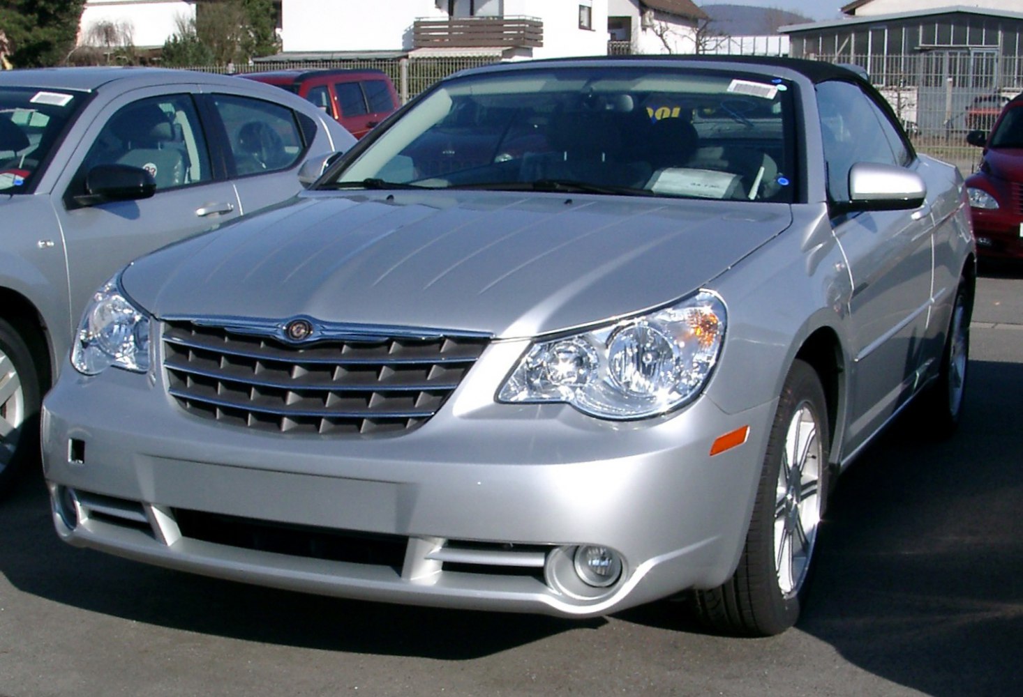Front view of silver convertible with distinct headlights and grille, black soft top