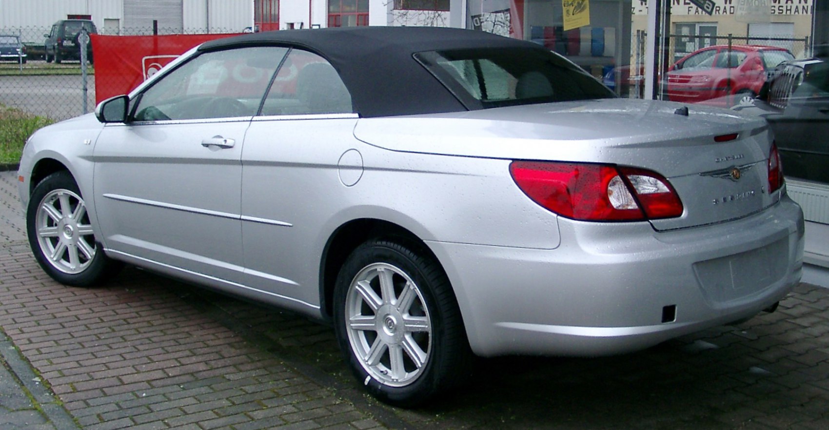 Rear side of a convertible with soft fabric roof and silver alloy wheels