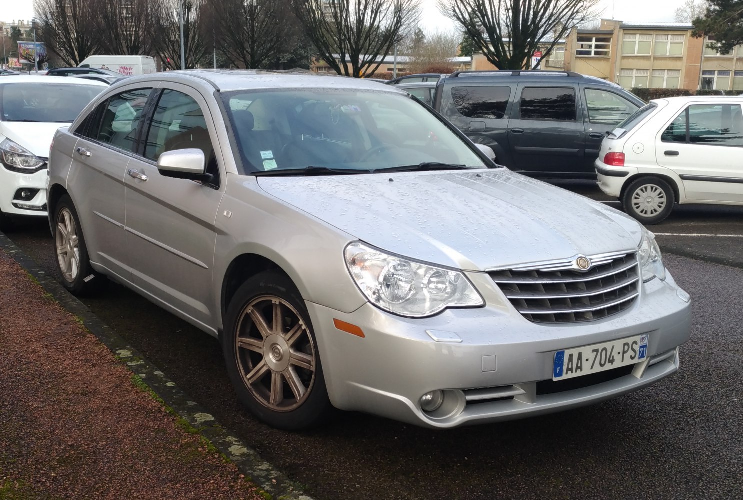 Silver sedan front right side view with clear headlights and alloy wheels.
