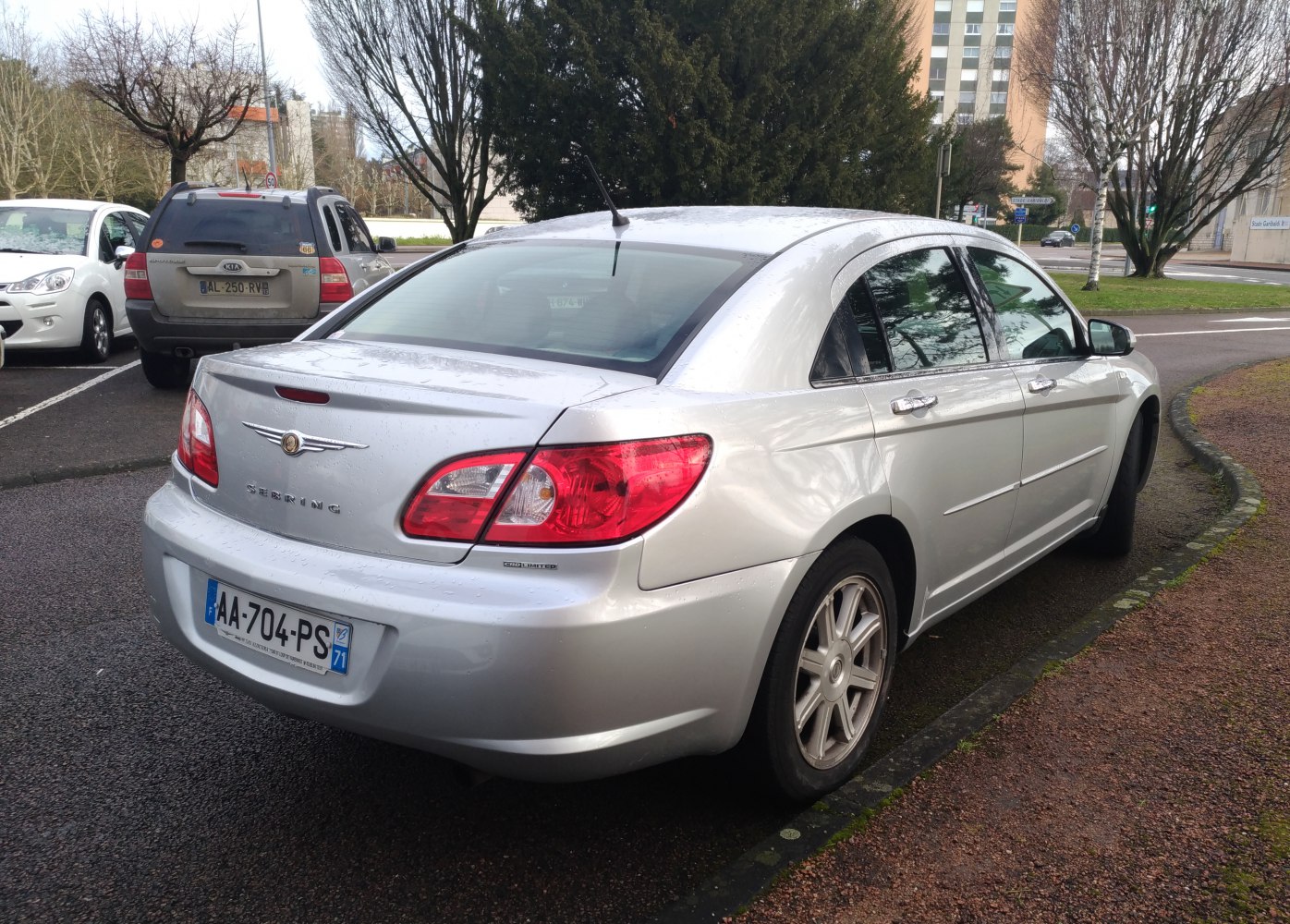 Rear side view of a silver sedan with red tail lights and chrome trim