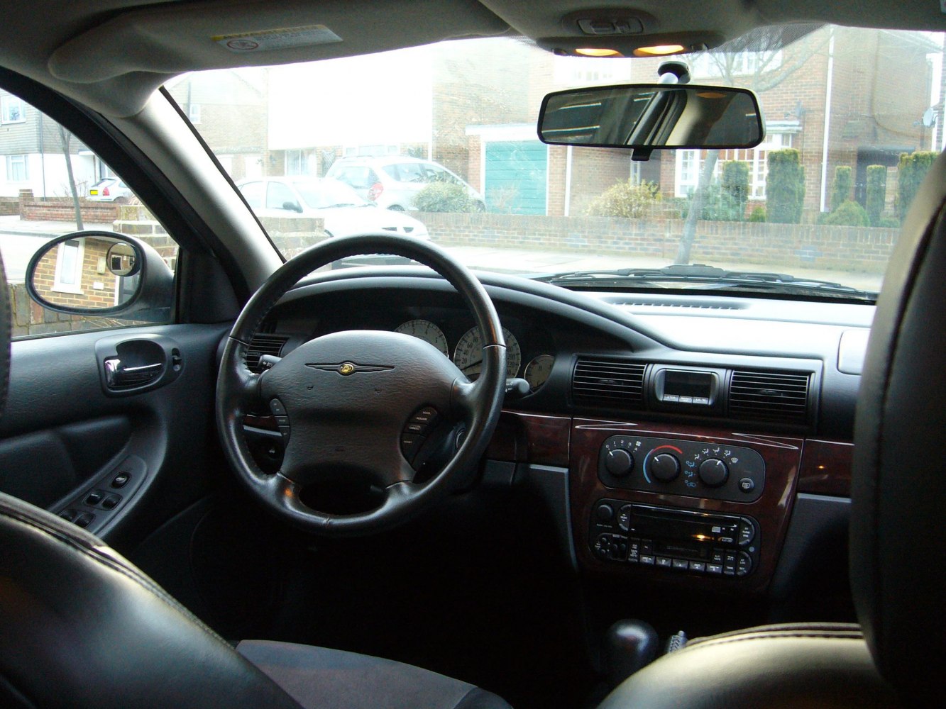 Steering wheel and dashboard with wood trim and control panels.