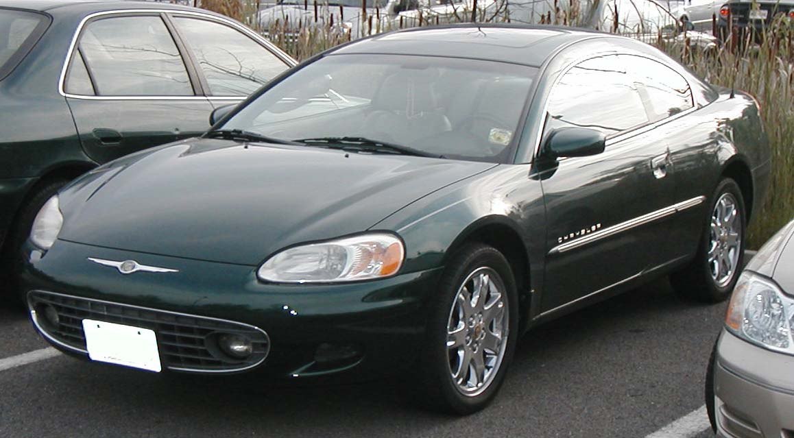 Front angle view of dark green coupe with chrome wheels and sleek headlights