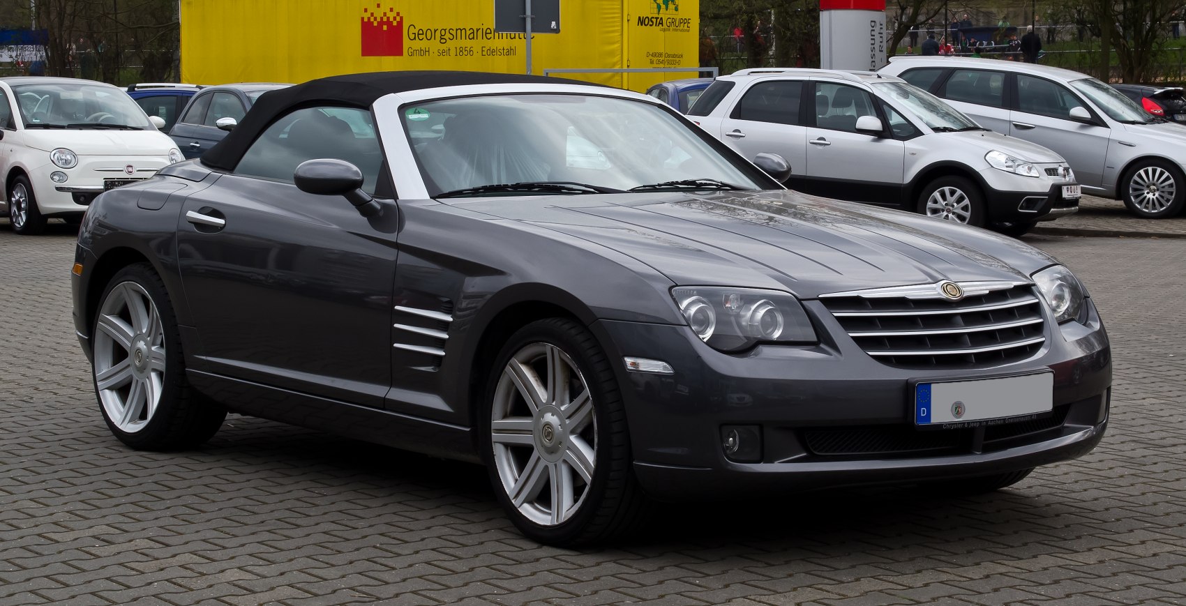 Front side view of a convertible roadster with soft top and alloy wheels
