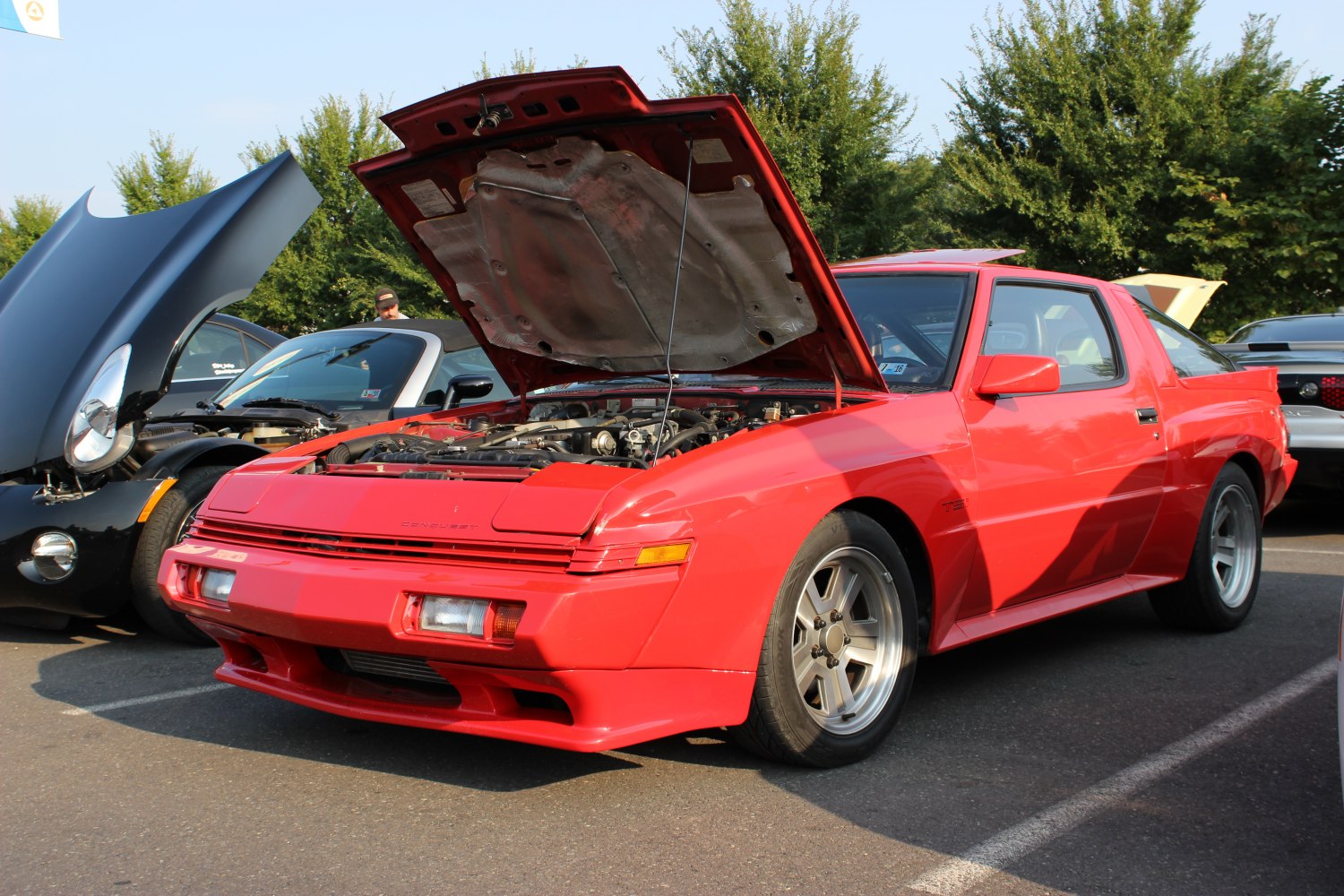 Red two-door coupe with open hood revealing engine bay.