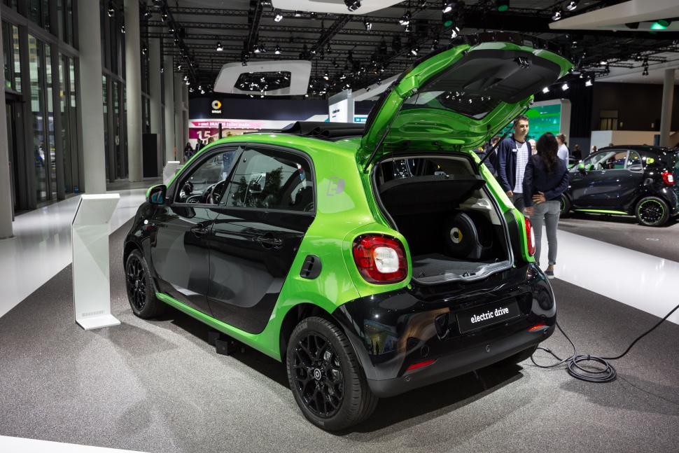 Rear view of electric vehicle with open trunk and charging cable