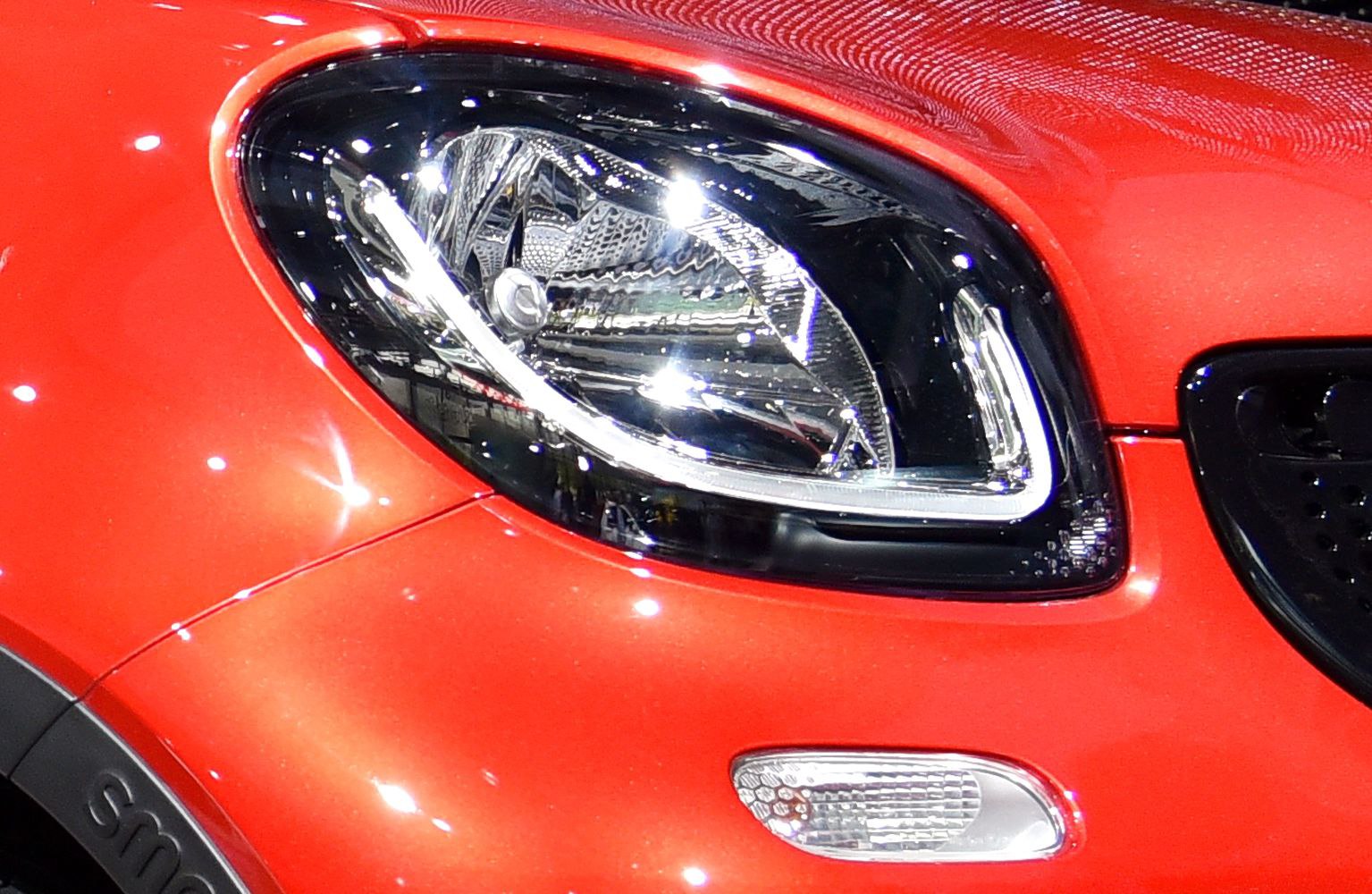 Close-up of sleek headlight with daytime running light and front signal on red vehicle