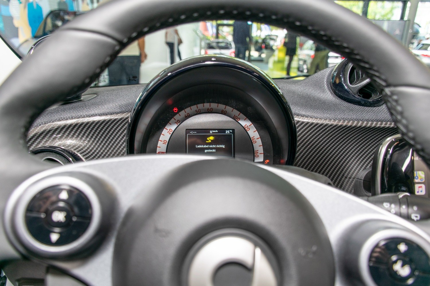 Close-up of speedometer and steering wheel with carbon fiber dashboard trim