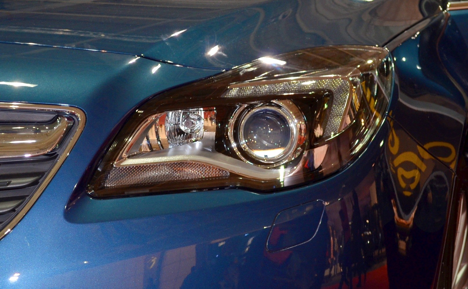 Close-up of modern projector headlight with LED strip and reflective elements.