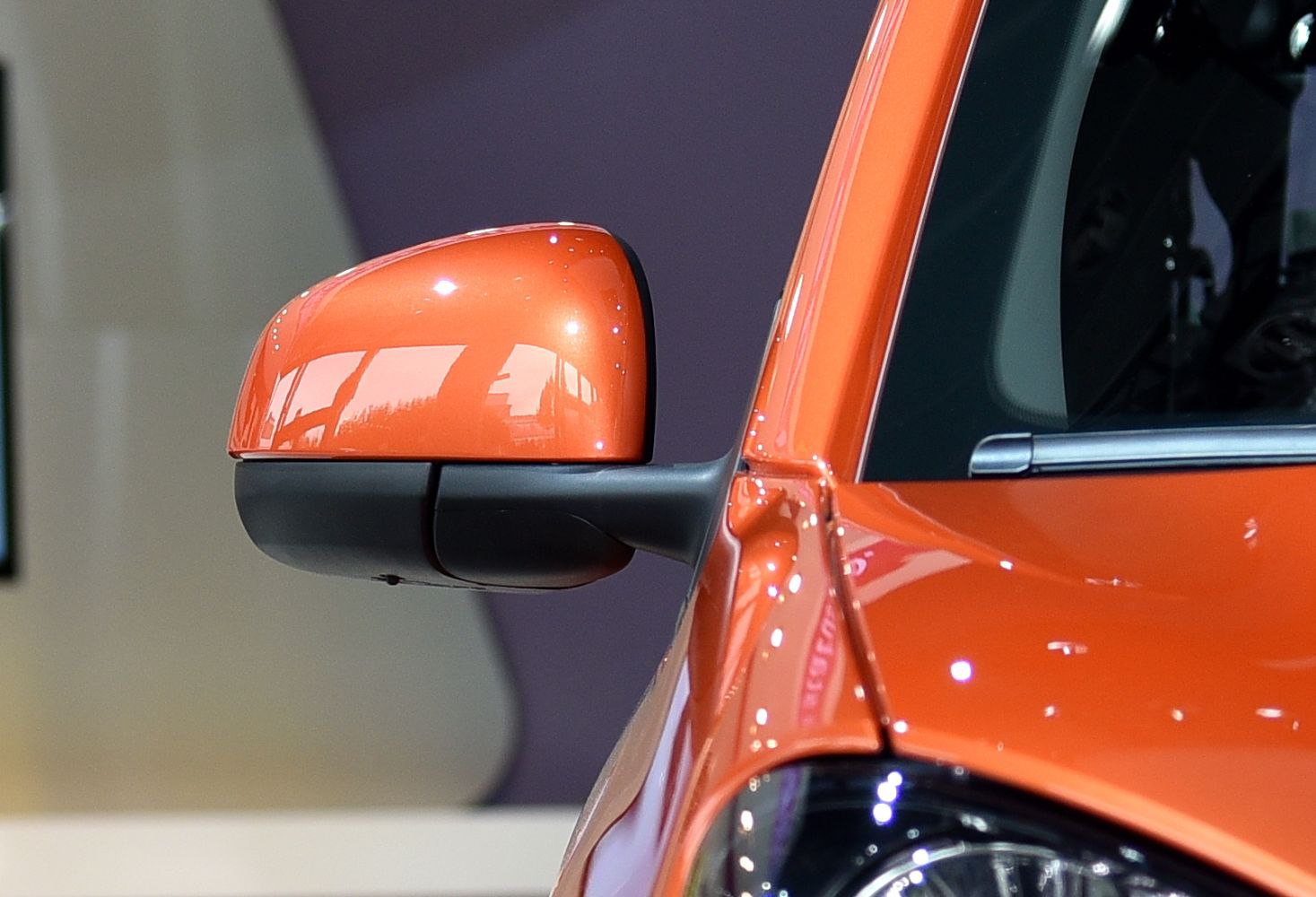 Close-up of orange car side mirror and door edge