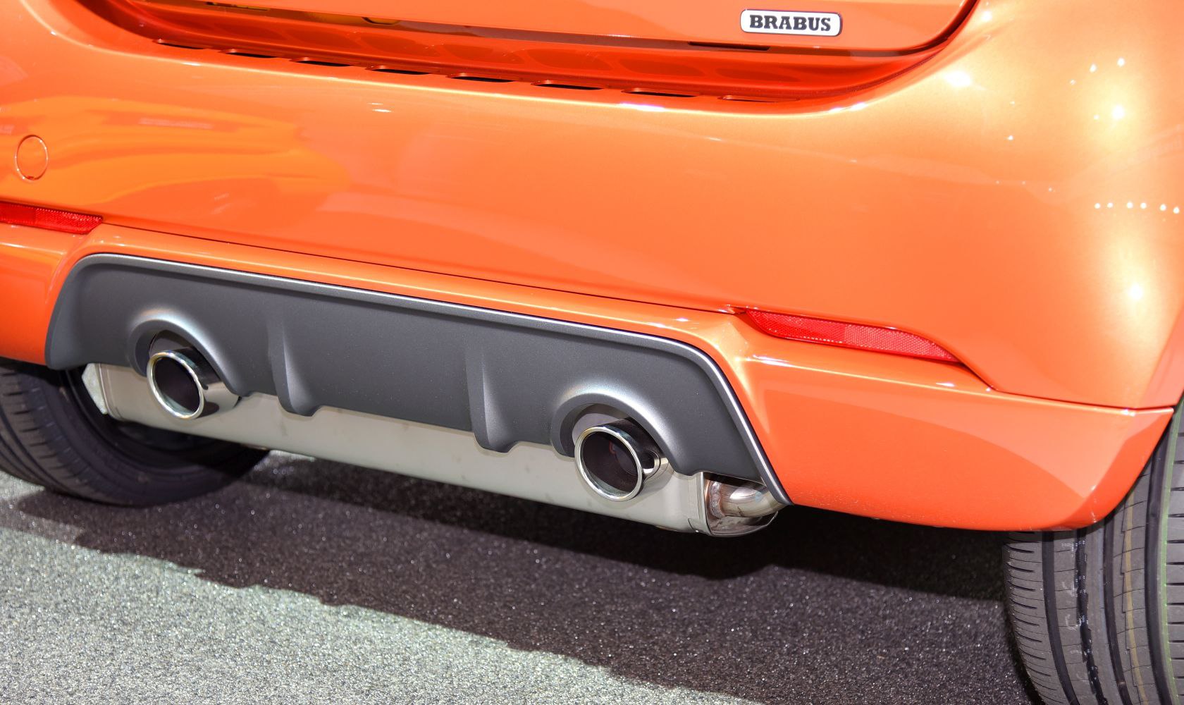 Dual chrome exhaust pipes with black rear diffuser and orange bumper