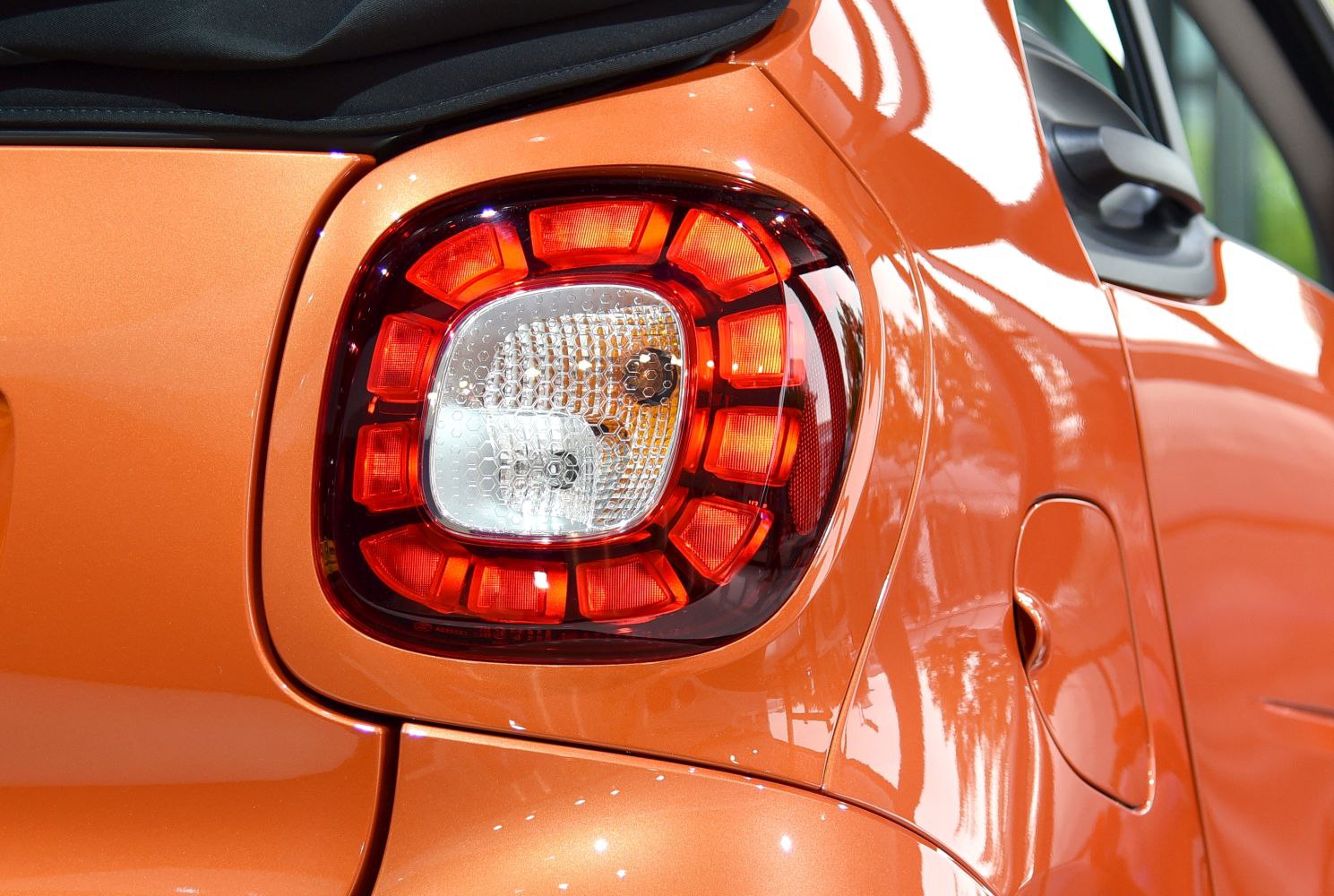 Close-up of the rear tail light with surrounding orange car body.