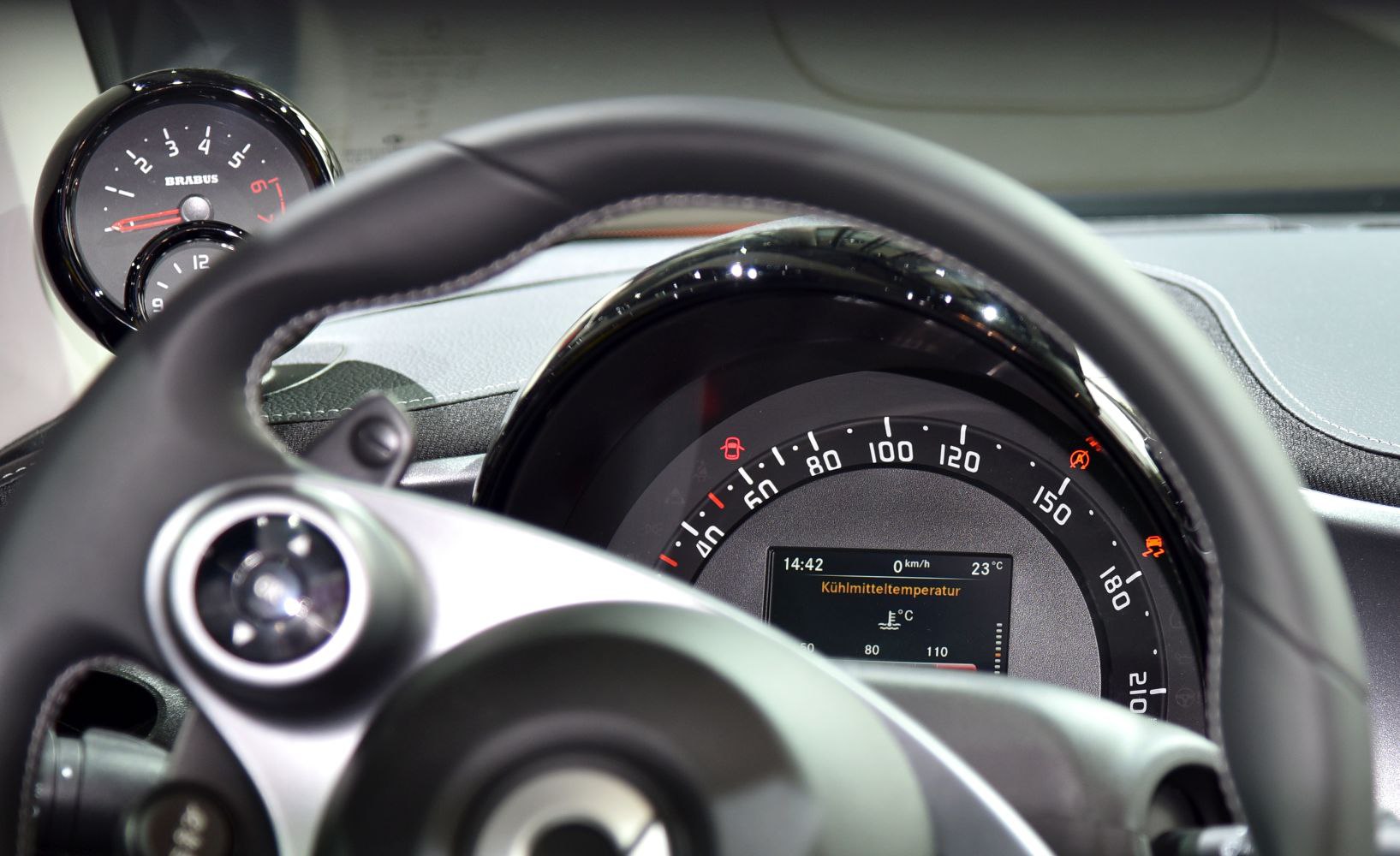 Tachometer and steering wheel inside car interior.