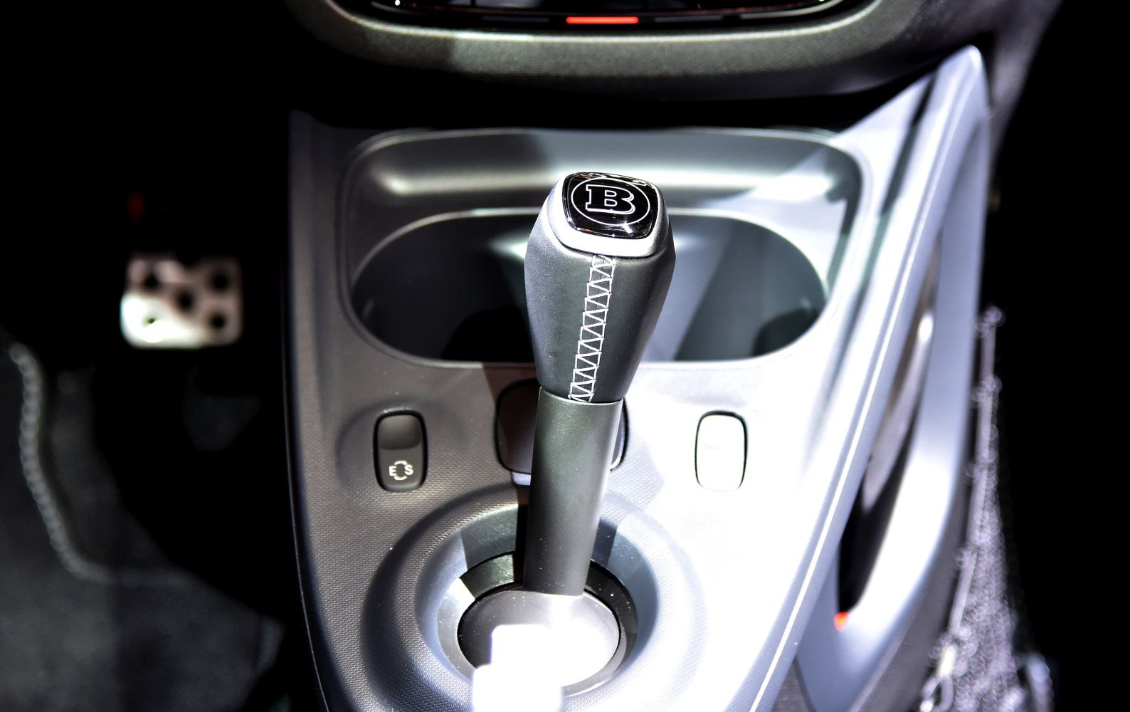 Close-up of gearshift lever with stitched leather and 'B' emblem.