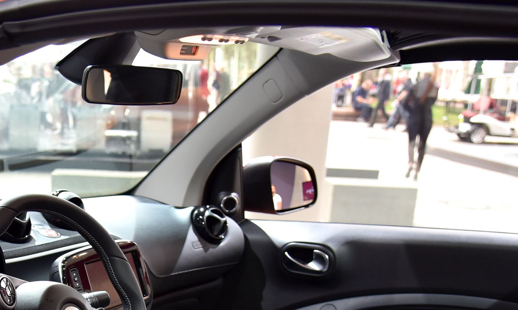 Dashboard, steering wheel, and side mirror in compact car cabin