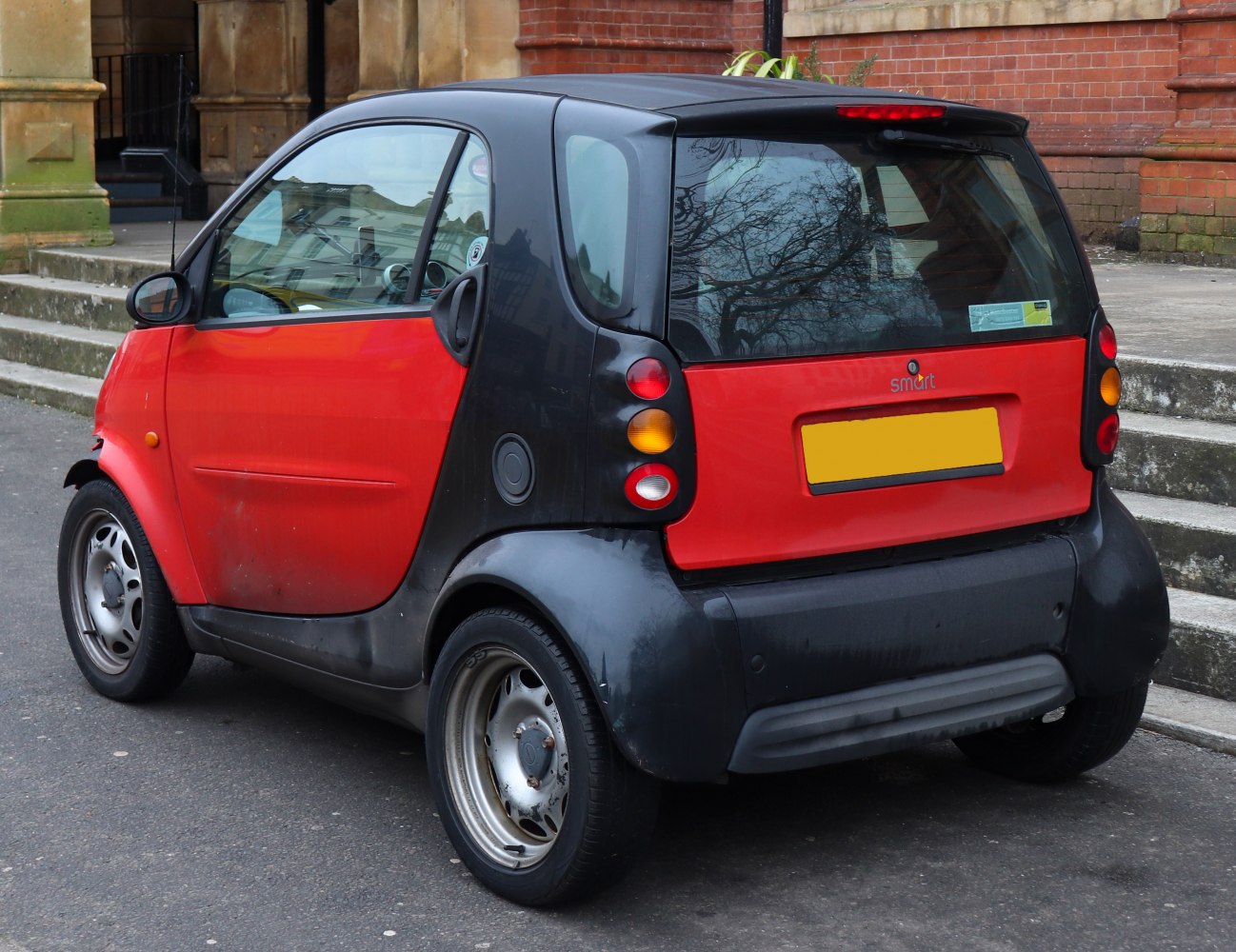 Rear view of compact two-tone small city car with distinctive round tail lights.